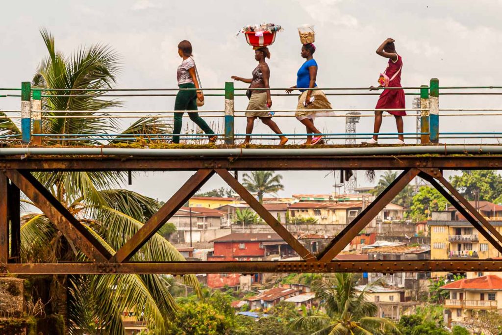 Frauen überqueren die alte Eisenbahnbrücke von Freetown, die Tengbeh-Brücke, und tragen dabei Waren auf dem Kopf / © Foto: Georg Berg