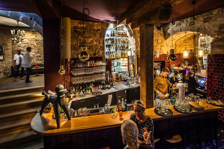 Pôle d'attraction en soirée : le Pudelbar. L'habillage du comptoir est au moins aussi remarquable que le caniche. Il est constitué de la tôle rouillée d'une vieille grange que Rainer Holzhauer a découverte lors d'une promenade à cheval / © Photo : Georg Berg