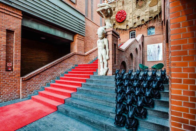 Le hall d'entrée impressionnant de l'hôtel Blow up 5050, Poznan. La Pologne. En tant que client, on a tout de suite envie de suivre le tapis rouge. Il passe devant des œuvres d'art contemporain comme des sculptures et des photographies. Le client de l'hôtel est conduit directement au bar de l'hôtel, lui aussi gigantesque / © Photo : Georg Berg