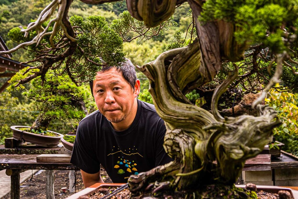Portrait du maître bonsaï et propriétaire du jardin Toshio Ohsugi avec un arbre de soins vieux de 500 ans. Selon les archives, l'arbre a été prélevé sur un rocher dans les montagnes vers 1920. Ses racines avaient creusé une fente dans la roche / © Photo : Georg Berg