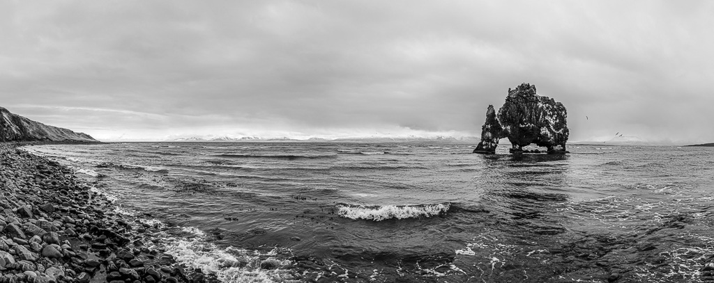 Le rocher appelé Hvítserkur Troll est visible depuis une plage de sable noir. Cet îlot de basalte de 15 mètres de haut ressemble à un dragon ou à un rhinocéros. / © Photo : Georg Berg