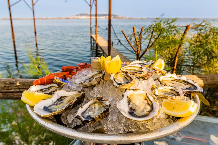 Plateau d'huîtres et fruits de mer au pavillon de plage Le St Pierre Tarbouriech. Derrière la lagune se trouve la ville de Sète / © Photo : Georg Berg