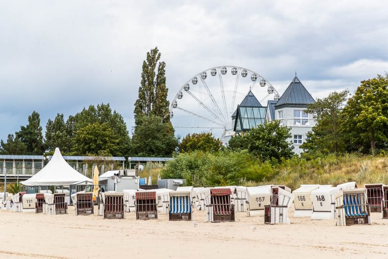 Chaises de plage sur la plage d'Ahlbeck avec une grande roue en arrière-plan. La chaise de plage a été inventée en 1882 à Rostock, sur la mer Baltique, par le vannier Bartelsmann. La fabrication individuelle pour une dame aristocratique âgée pour la plage de Warnemünde est devenue un meuble de location très apprécié. Elisabeth Bartelsmann, l'épouse du vannier, s'est rendu compte que ce meuble lié à un lieu et à une saison se louait mieux qu'il ne se vendait / © Photo : Georg Berg
