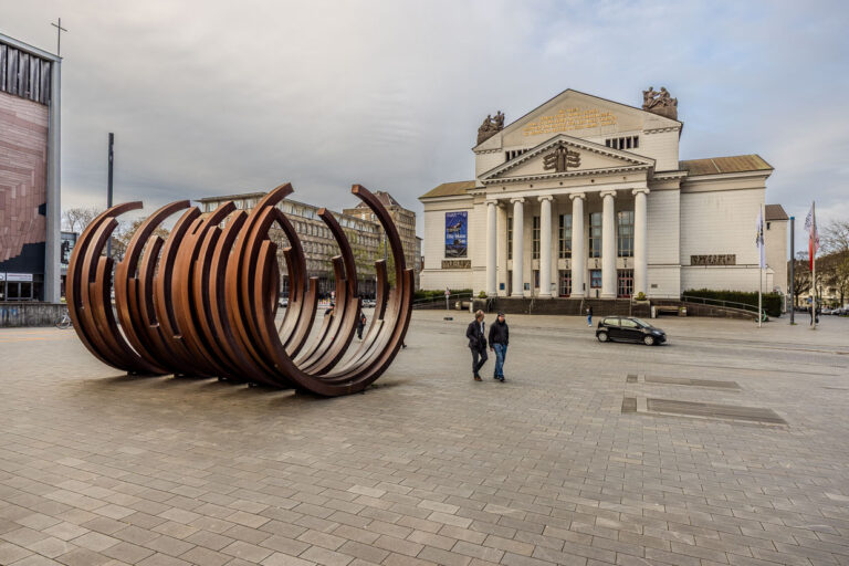 Zwei Männer gehen an einer Skulptur vorbei vor dem Theater Duisburg, Deutschland