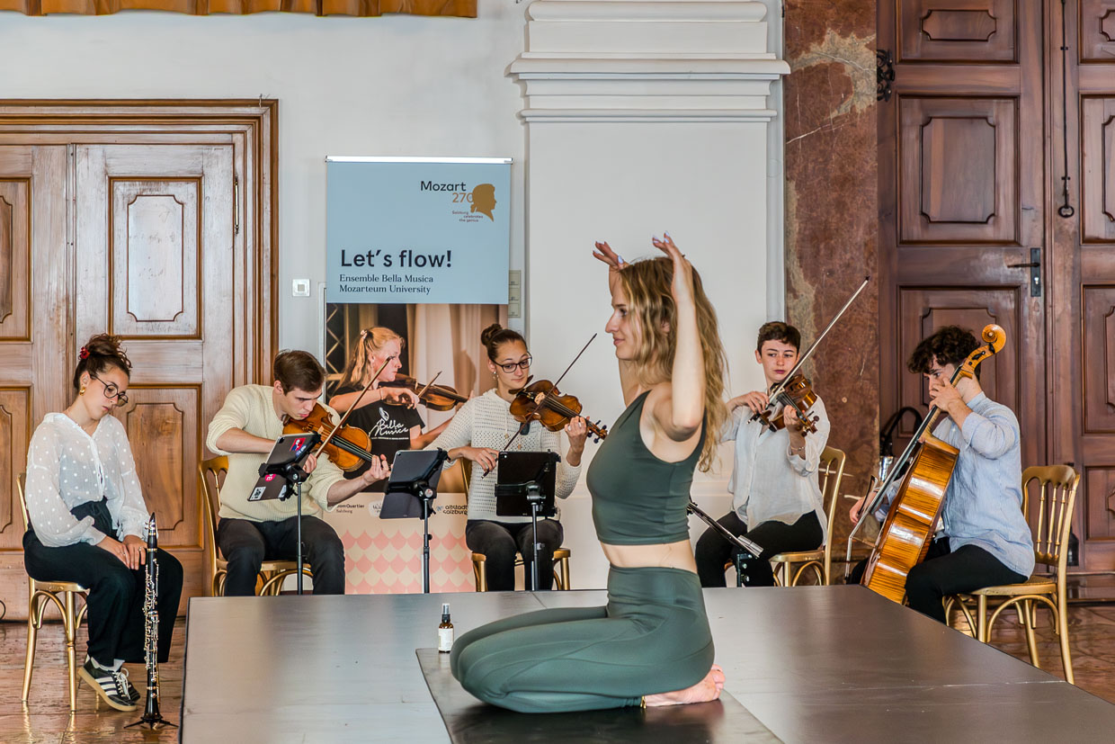 Eine Frau bewegt sich fließend vor einem klassischen Musikensemble am Domplatz in Salzburg Austria